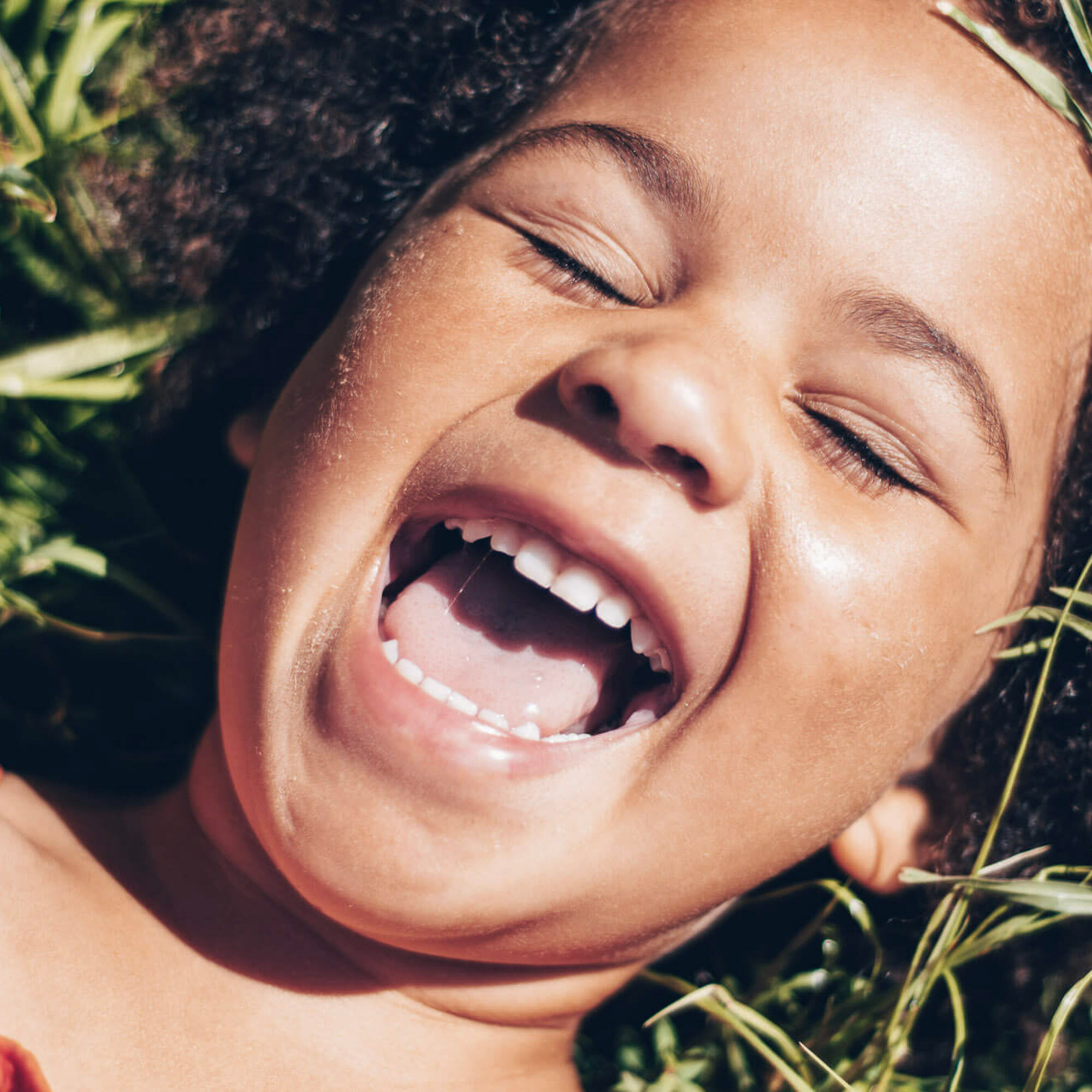 child smiling while laying in the grass